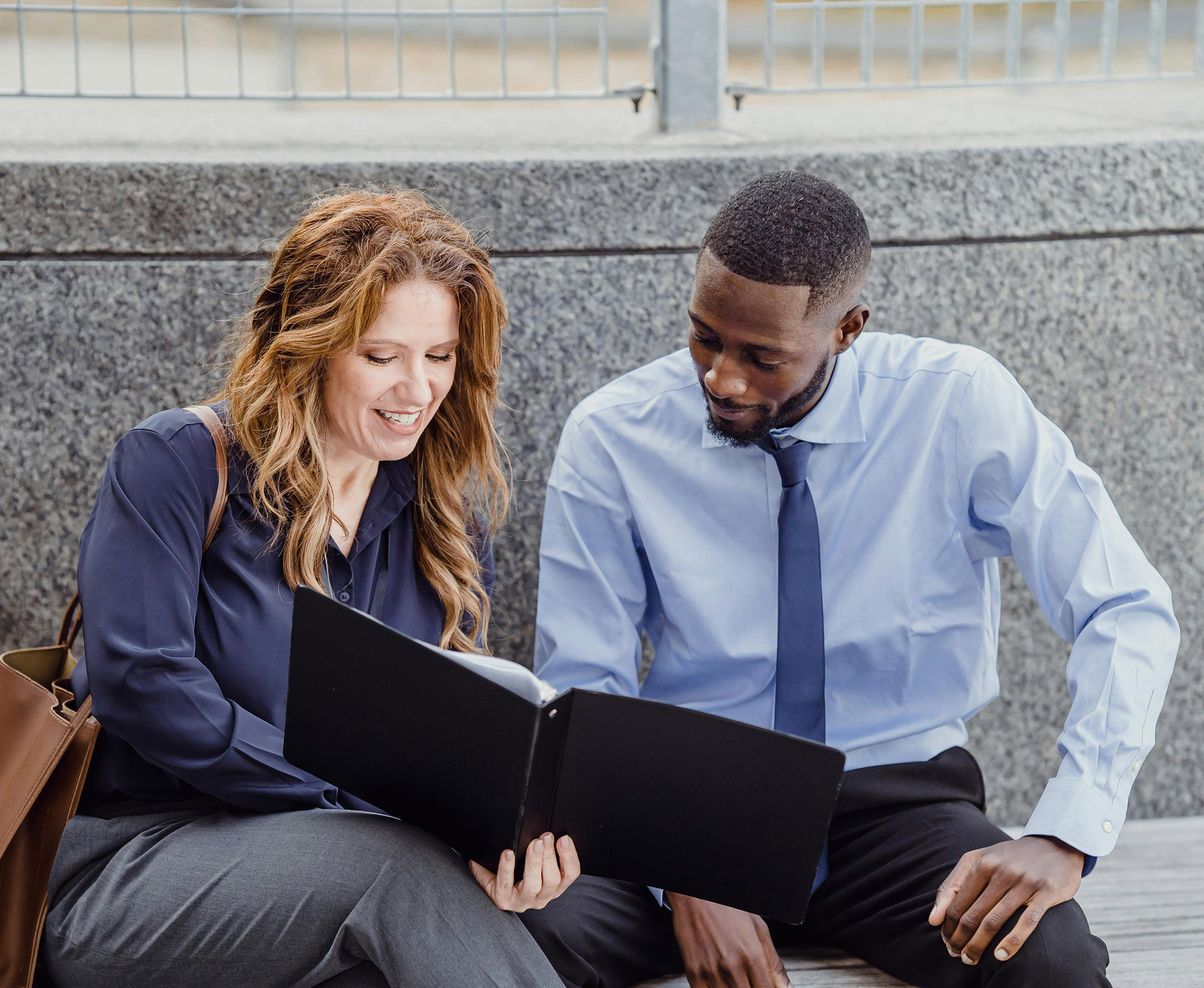 Photo shows two people reviewing the same notes. They are sitting in a lobby of a building