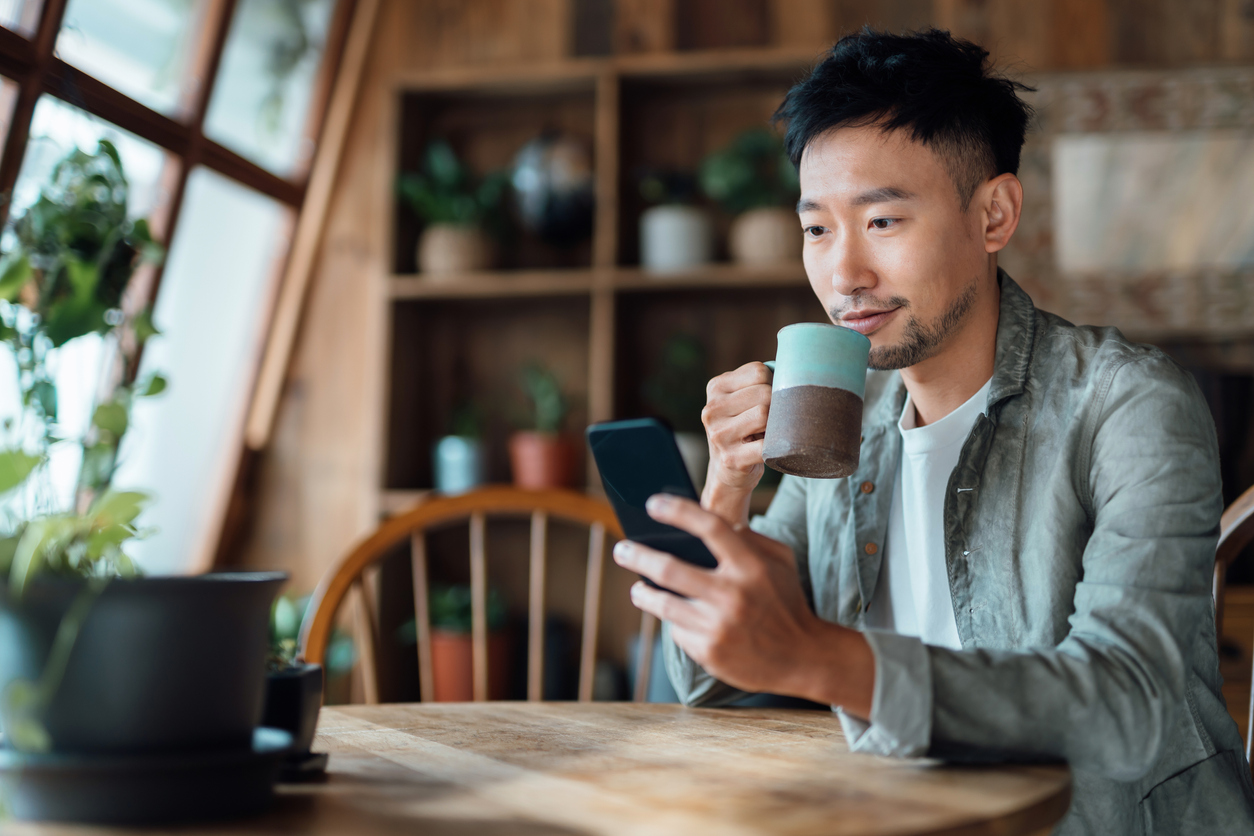 Young Asian man managing online banking with mobile app on smartphone