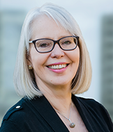 Susan Silma headshot. She is wearing a black blouse and has glasses.